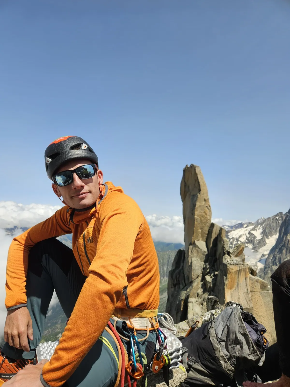 Valentin Palardy en montagne, casque sur la tête, devant une aiguille rocheuse